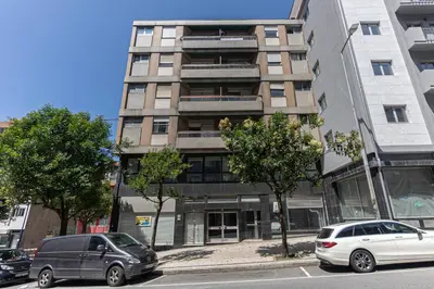 two cars parked in front of a tall building at Now Trindade in Porto