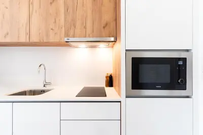 a white kitchen with a microwave and a sink at Feel Porto Lapa Collection Flats in Porto