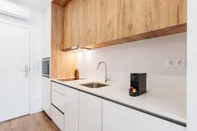 a kitchen with white cabinets and a sink at Feel Porto Lapa Collection Flats in Porto