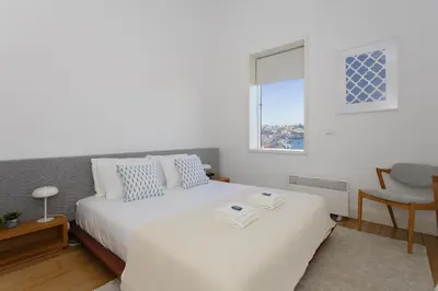 a white bedroom with a bed and a window at Local 167 - Oporto View House in Vila Nova de Gaia