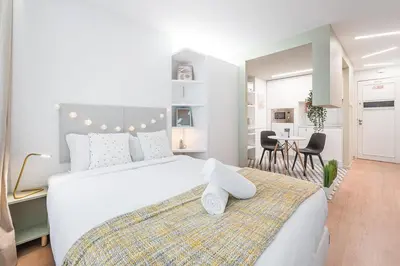 a bedroom with a large white bed and a dining room at GuestReady - Fabric Porto Apartment in Porto