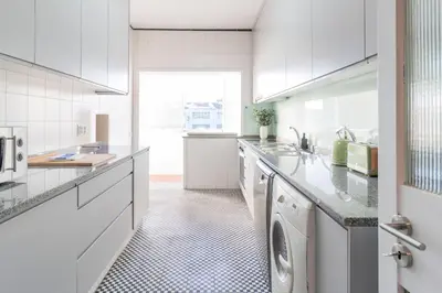 a white kitchen with a washer and dryer at 3BR Joyous Wonder by LovelyStay in Porto