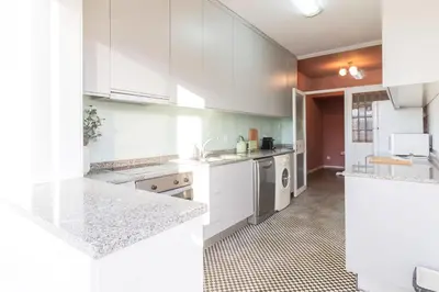 a white kitchen with white cabinets and appliances at 3BR Joyous Wonder by LovelyStay in Porto