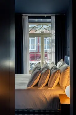 a bedroom with a bed with pillows and a window at Hotel Kodawari Flores - by Kodawari Residences in Porto