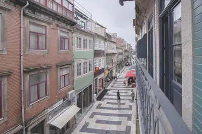 a city street with buildings and people walking on a balcony at Once Upon In Porto Apartments II in Porto