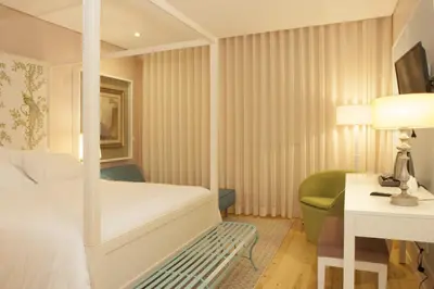 a bedroom with a white bed and a green chair at In Porto Gallery Guesthouse in Porto