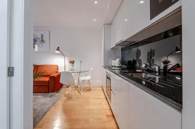 a kitchen with white cabinets and a white table at Almada Prime Apartment I in Porto