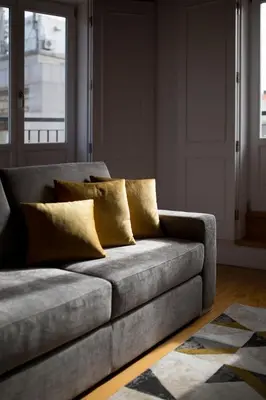a grey couch with yellow pillows in a living room at Almada Prime Apartment II in Porto