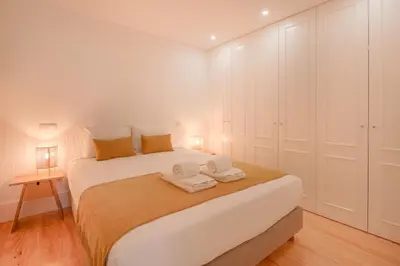 a bedroom with a large white bed with towels on it at Canto Flores in Porto