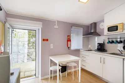 a kitchen with white cabinets and a table and chairs at Island House in Porto