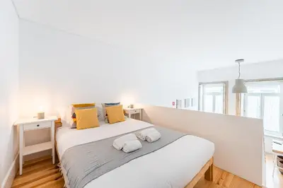a white bedroom with a large bed with yellow pillows at GuestReady - A lovely city retreat in Porto
