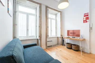 a living room with a blue couch and two windows at GuestReady - A lovely city retreat in Porto