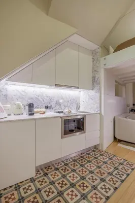 a kitchen with white cabinets and a tile floor at Tailor's Apartments II in Porto