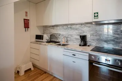 a kitchen with white cabinets and a sink at Downtown Urban Nest in Porto