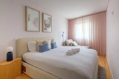 a bedroom with a large white bed with blue pillows at Modern Camões Flat, In the Heart of Porto in Porto
