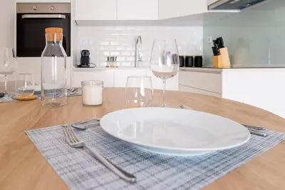a table with a plate and wine glasses on it at Modern Camões Flat, In the Heart of Porto in Porto