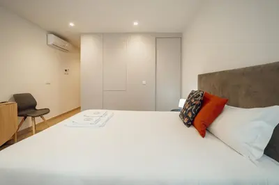 a bedroom with a large white bed and a chair at Carmo Residence Porto by Vacationy in Porto