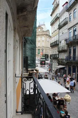 a balcony with people sitting at tables on a city street at Porto with History in Porto