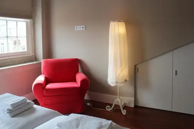 a red chair in a room with a bed and a window at Porto with History in Porto