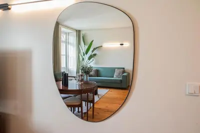 a mirror reflecting a living room with a blue couch at The Luxe Cube Apartment in Porto