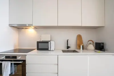 a kitchen with white cabinets and a microwave at Chic 1BR in República w Balcony by LovelyStay in Porto