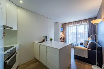 a kitchen with white cabinets and a living room at Bellevue Oporto Downtown in Porto