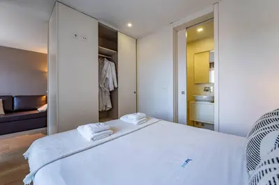 a bedroom with a large white bed and a bathroom at Bellevue Oporto Downtown in Porto