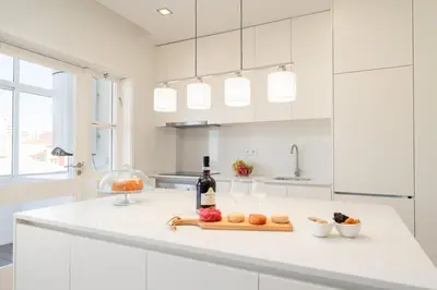 a white kitchen with a bottle of wine and fruit on a counter at Bright & Spacious Retreat with Balcony by HostWise in Porto
