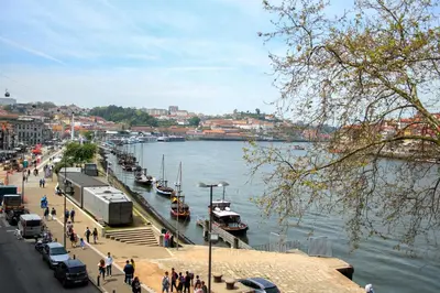 a group of people walking along a river with boats at T3 suites com vistas rio Douro in Vila Nova de Gaia