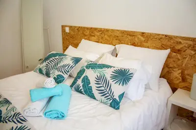 a bed with white and green pillows and a blue towel at T3 suites com vistas rio Douro in Vila Nova de Gaia