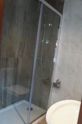 a shower with a glass door next to a toilet at Casa no centro histórico in Vila Nova de Gaia
