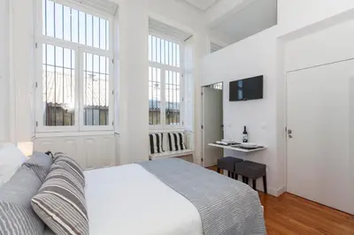 a white bedroom with a bed and windows at BO - Sá da Bandeira in Porto