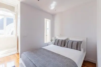a white bedroom with a bed and a window at BO - Sá da Bandeira in Porto