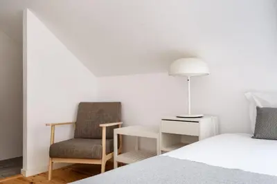 a bedroom with a bed and a chair and a lamp at Mezzanine Studio in the City Center in Porto