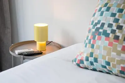 a bed with a table with a lamp and a pillow at GuestReady - Welcoming place in Porto in Porto