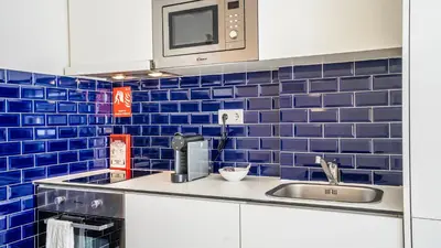 a blue tiled kitchen with a sink and a microwave at TrindadeFlat w AC by LovelyStay in Porto