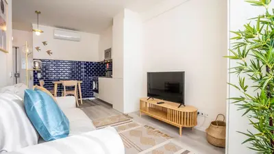 a living room with a white couch and a tv at TrindadeFlat w AC by LovelyStay in Porto