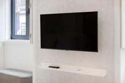 a white living room with a tv and a couch at 252 Heroísmo Duplex Flat in Porto