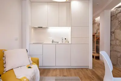 a kitchen with white cabinets and a yellow couch at St Ildefonso 04 in Porto