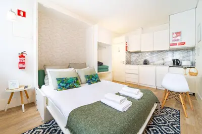 a small bedroom with a white bed and a kitchen at Cosy Charm Bonfim in Porto