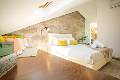 a bedroom with a large bed and a stone wall at CHARM by YoursPorto in Vila Nova de Gaia