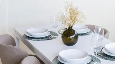 a white table with plates and glasses and a vase with flowers at 2BR Home near Douro River by LovelyStay in Vila Nova de Gaia