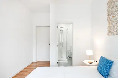 a white bedroom with a bed and a bathroom at ViVA Bright & Spacious Gaia in Vila Nova de Gaia