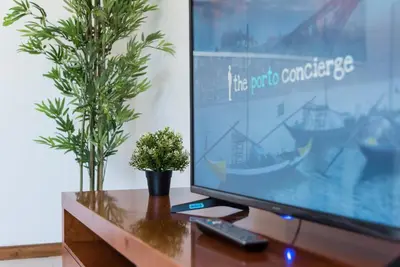 a computer monitor on a wooden table with a potted plant at GuestReady - Porto Panoramic View in Vila Nova de Gaia