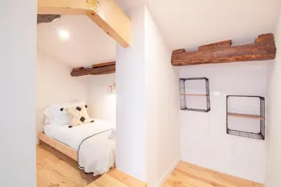 a bedroom with a bed and white walls and wood floors at Olive Tree House by LovelyStay in Porto