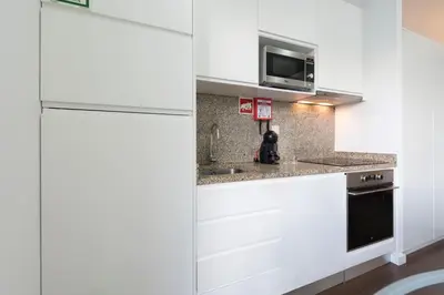 a kitchen with white cabinets and a refrigerator at Apartment Boavista Roundabout by Sweet Porto in Porto
