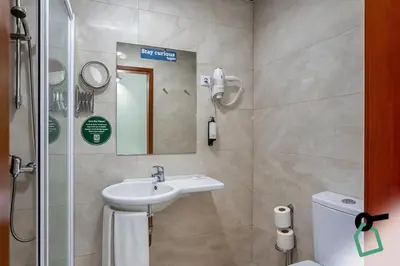a bathroom with a sink and a toilet and a mirror at HOTIDAY Room Collection - Oporto in Porto
