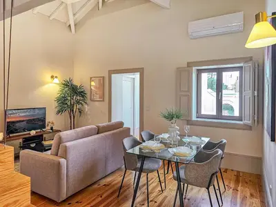 a living room with a couch and a table and chairs at Wood Haven Luxury Duplex Downtown Porto with AC in Porto