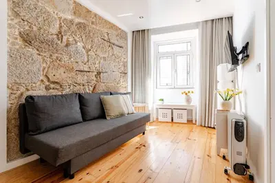 a living room with a couch and a stone wall at Cozee Bonjardim in Porto