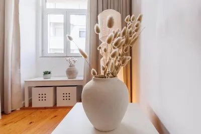 a white vase sitting on a table with flowers in it at Cozee Bonjardim in Porto